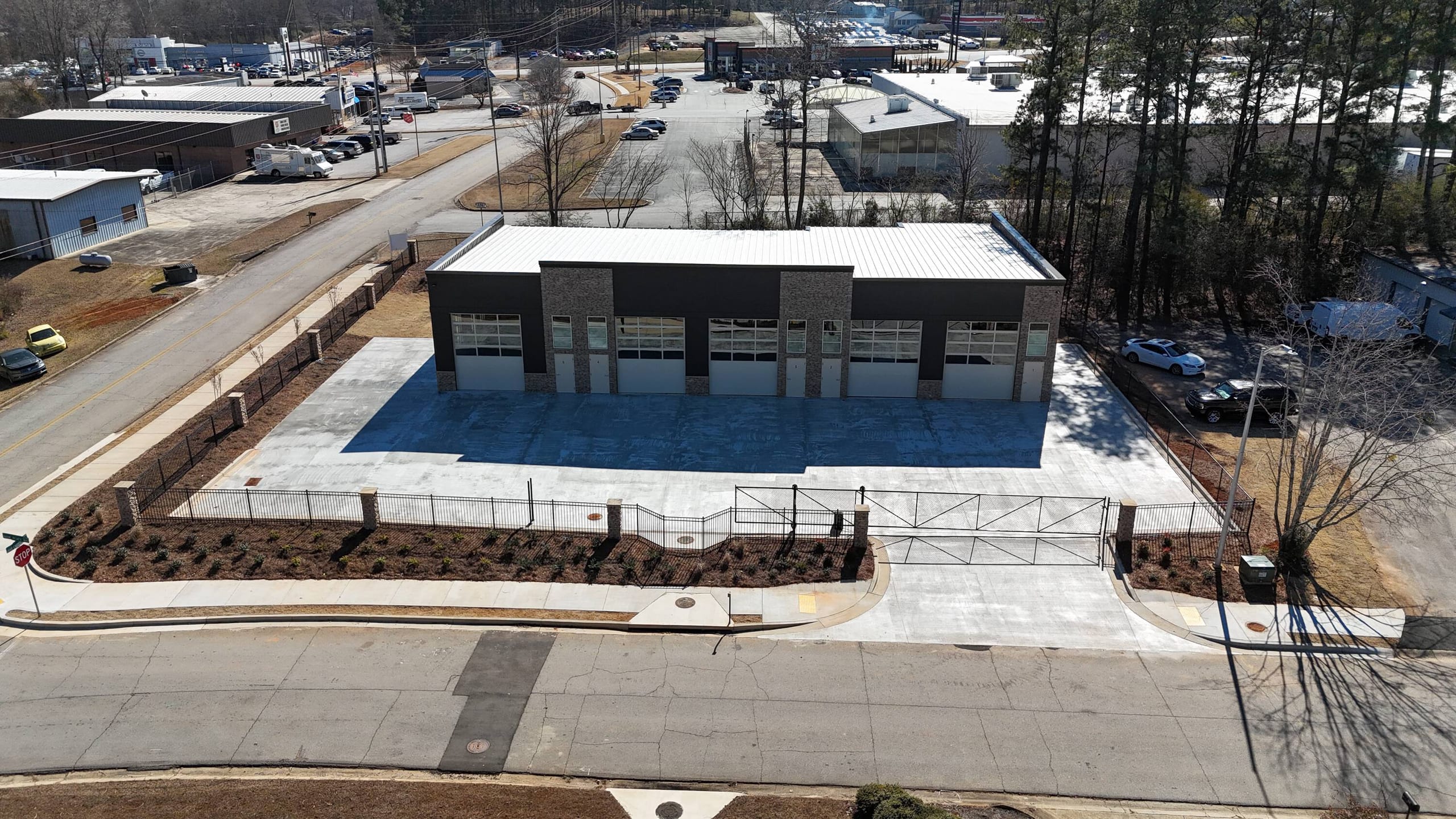 Aerial view of the Carrollton Flex Park building with a row of overhead doors and gated, landscaped lot