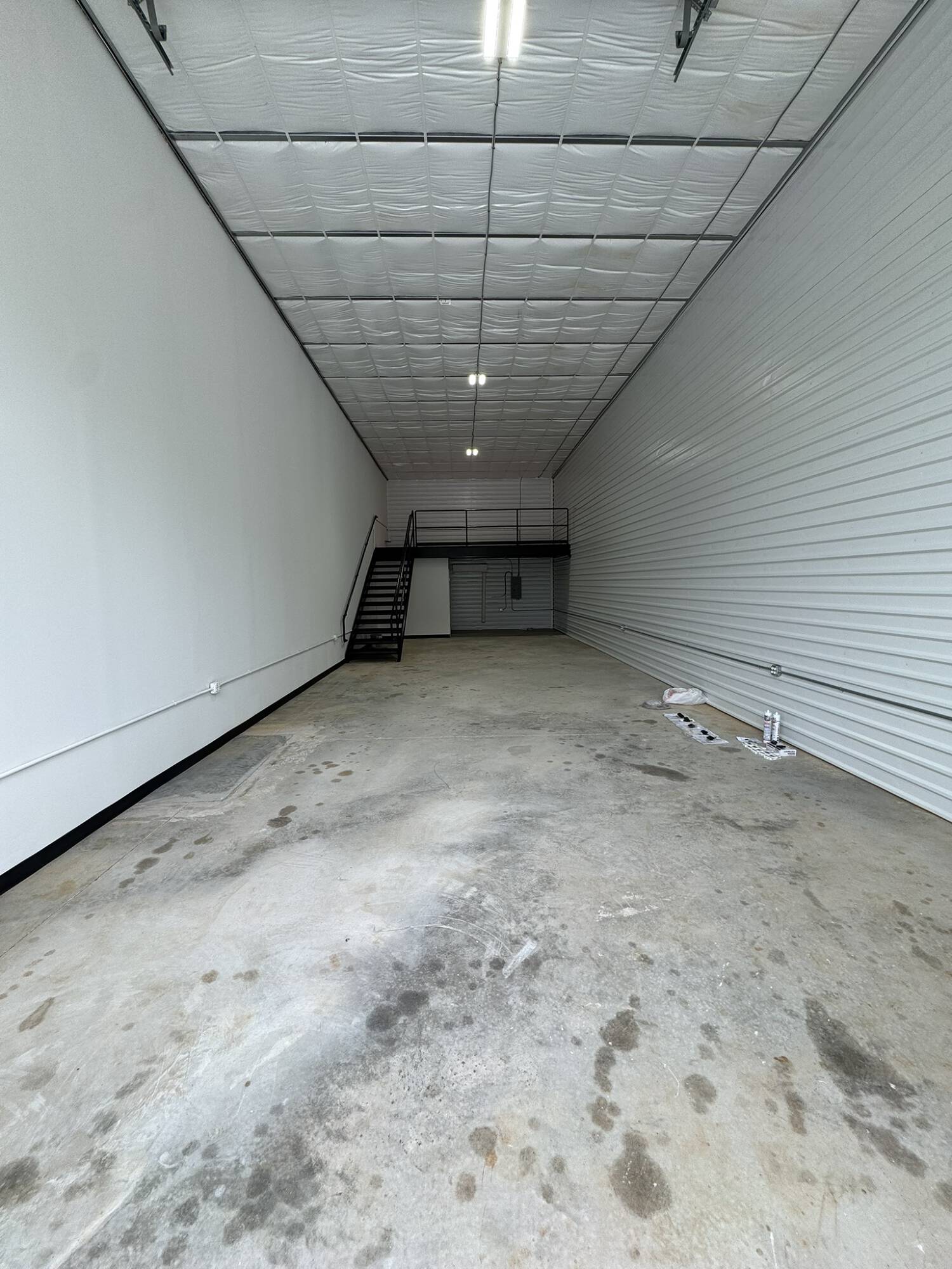 Interior flex unit with a steel staircase leading up to a mezzanine loft platform